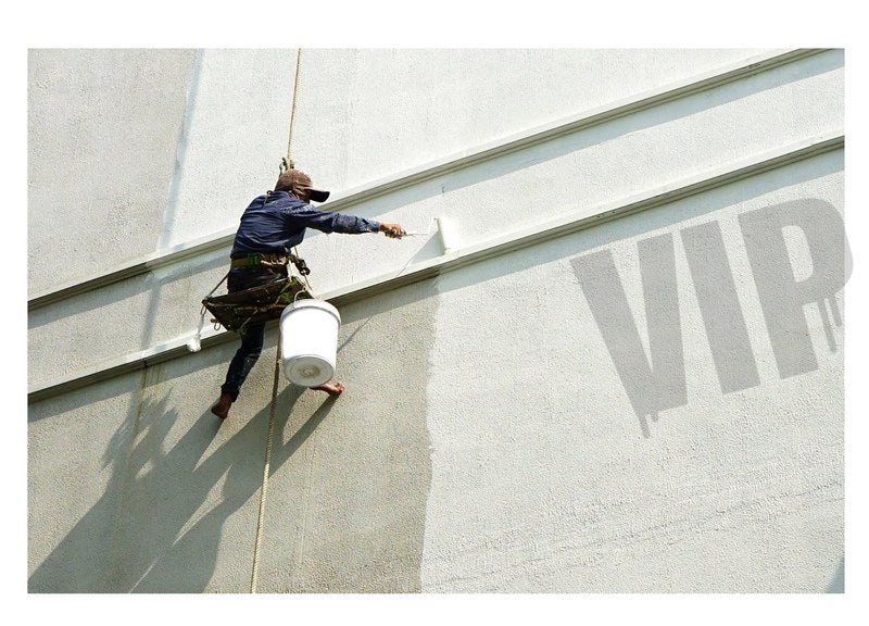 Schilder hoog op de gevel, VIP logo aan het schilderen